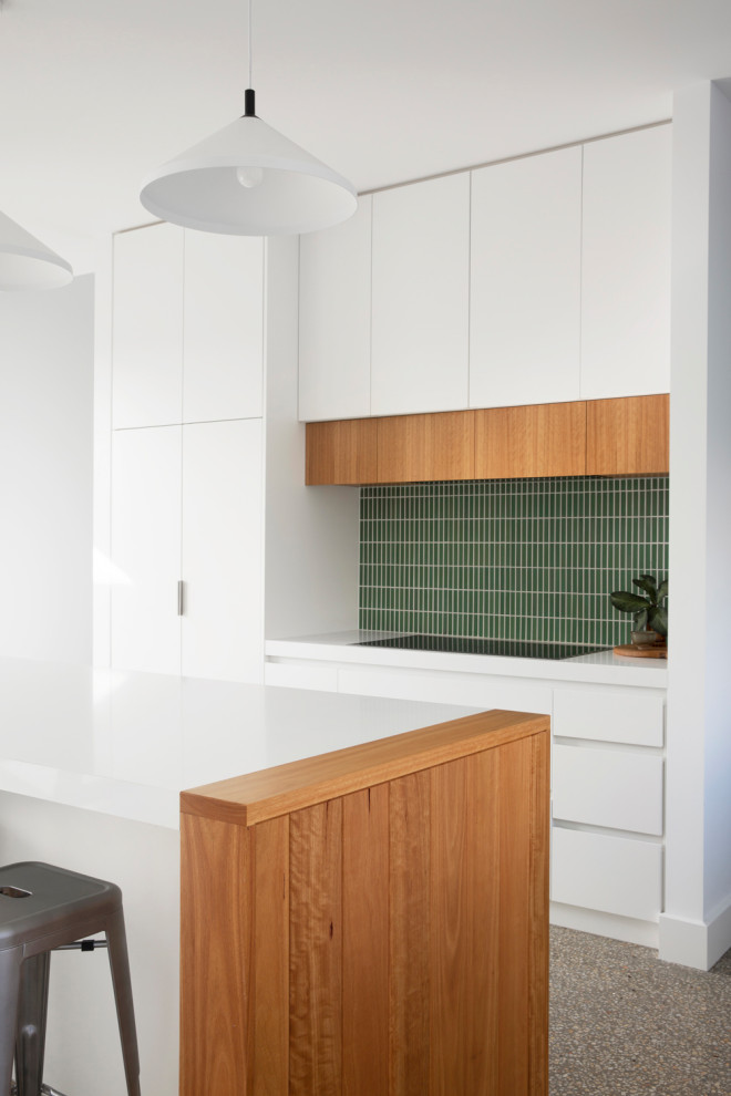 Exempel på ett mellanstort maritimt vit vitt kök, med en undermonterad diskho, släta luckor, vita skåp, bänkskiva i kvarts, grönt stänkskydd, stänkskydd i keramik, integrerade vitvaror, betonggolv, en köksö och grått golv