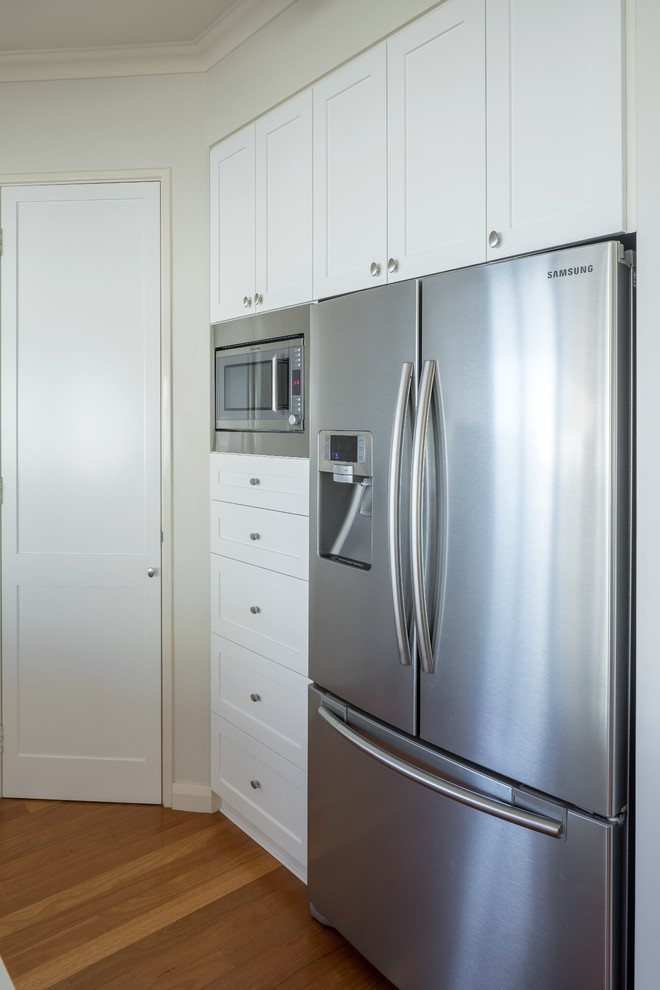 Imagen de cocina tradicional renovada con armarios estilo shaker, puertas de armario blancas y electrodomésticos de acero inoxidable