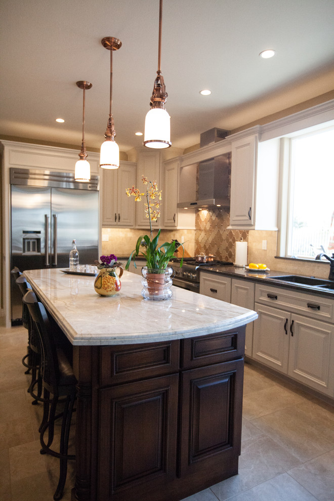 Eat-in kitchen - mediterranean l-shaped ceramic tile and beige floor eat-in kitchen idea in New Orleans with a double-bowl sink, recessed-panel cabinets, beige cabinets, soapstone countertops, beige backsplash, glass tile backsplash, stainless steel appliances and an island