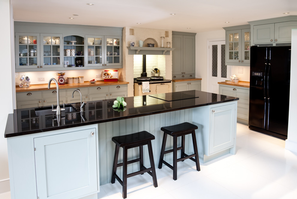 Example of a danish l-shaped kitchen design in London with a drop-in sink, recessed-panel cabinets, blue cabinets, white backsplash and an island