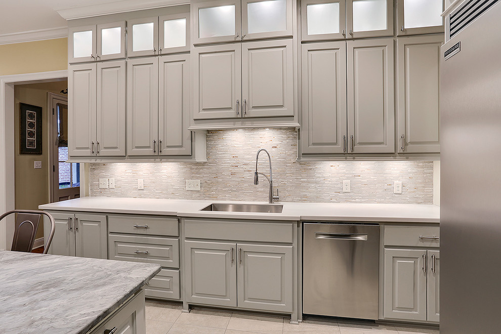 Eat-in kitchen - large transitional galley porcelain tile eat-in kitchen idea in New Orleans with an undermount sink, raised-panel cabinets, gray cabinets, quartzite countertops, gray backsplash, mosaic tile backsplash, stainless steel appliances and an island