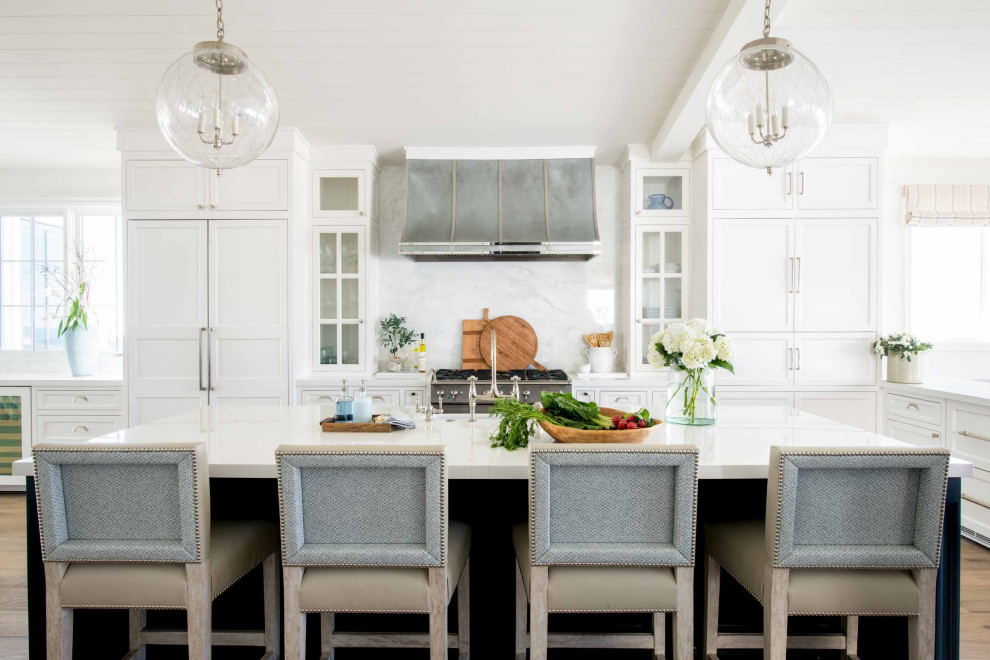 This is an example of a large nautical l-shaped kitchen in Los Angeles with recessed-panel cabinets, white cabinets, white splashback, stone slab splashback, integrated appliances, medium hardwood flooring, an island, brown floors, white worktops and a timber clad ceiling.
