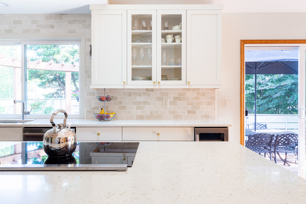 Modern inredning av ett mellanstort vit vitt kök, med en dubbel diskho, skåp i shakerstil, vita skåp, bänkskiva i kvarts, vitt stänkskydd, stänkskydd i keramik, rostfria vitvaror, mellanmörkt trägolv och en köksö