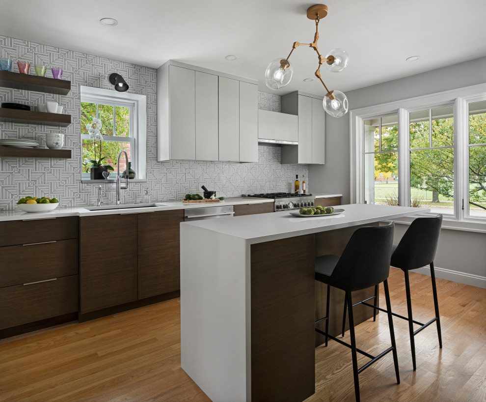 Medium sized modern l-shaped kitchen/diner in Detroit with a double-bowl sink, flat-panel cabinets, grey cabinets, engineered stone countertops, grey splashback, mosaic tiled splashback, stainless steel appliances, light hardwood flooring, an island and white worktops.