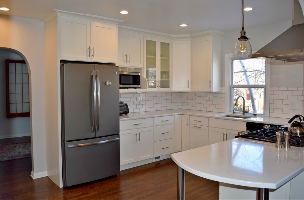 This is an example of a classic u-shaped kitchen/diner in Denver with a submerged sink, shaker cabinets, white cabinets, white splashback, metro tiled splashback, stainless steel appliances, medium hardwood flooring and no island.