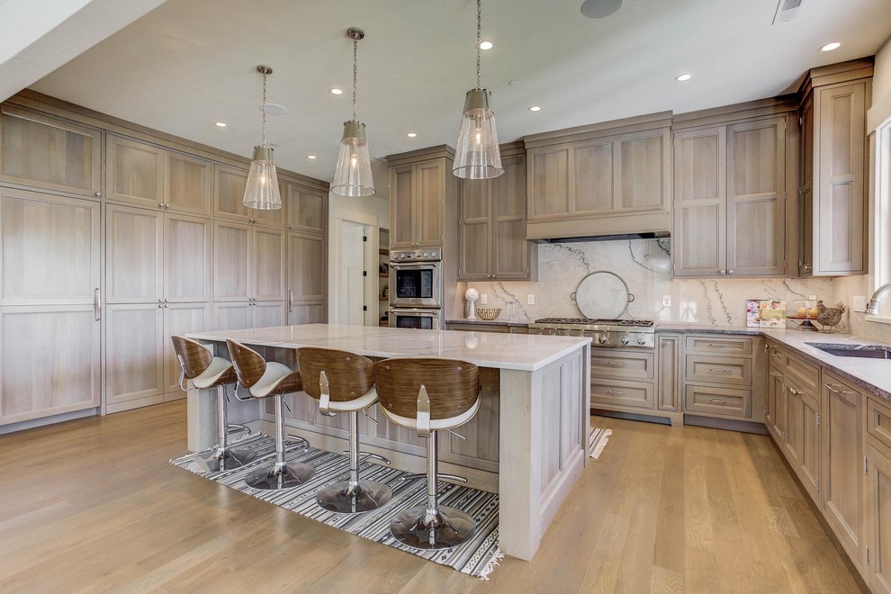 This is an example of an expansive traditional l-shaped open plan kitchen in Denver with a submerged sink, shaker cabinets, brown cabinets, white splashback, stainless steel appliances and an island.