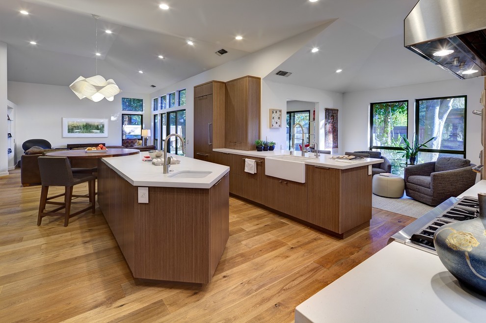 Design ideas for a large contemporary kitchen/diner in Sacramento with a belfast sink, shaker cabinets, medium wood cabinets, engineered stone countertops, grey splashback, ceramic splashback, stainless steel appliances, light hardwood flooring and an island.