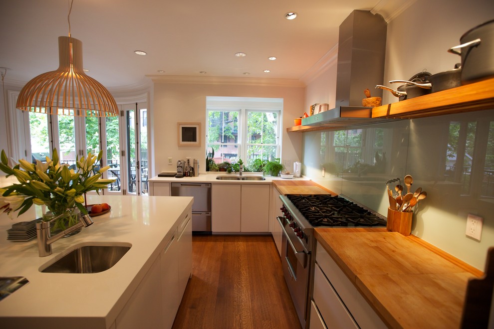 Trendy l-shaped eat-in kitchen photo in Boston with an undermount sink, flat-panel cabinets, white cabinets, quartz countertops, white backsplash, glass sheet backsplash and stainless steel appliances