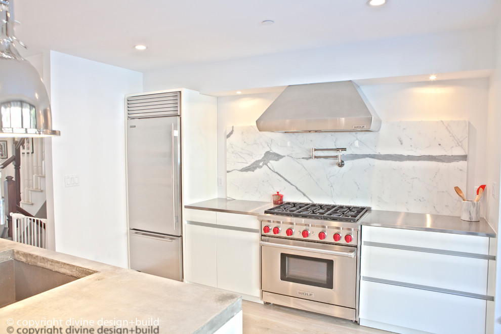 Exempel på ett modernt kök och matrum, med en undermonterad diskho, släta luckor, vita skåp, bänkskiva i rostfritt stål, vitt stänkskydd, rostfria vitvaror, ljust trägolv och en köksö