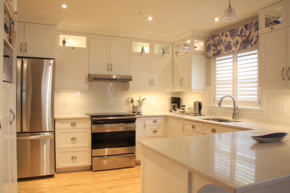 This is an example of a medium sized classic u-shaped kitchen/diner in Other with a submerged sink, shaker cabinets, white cabinets, white splashback, ceramic splashback, stainless steel appliances and a breakfast bar.