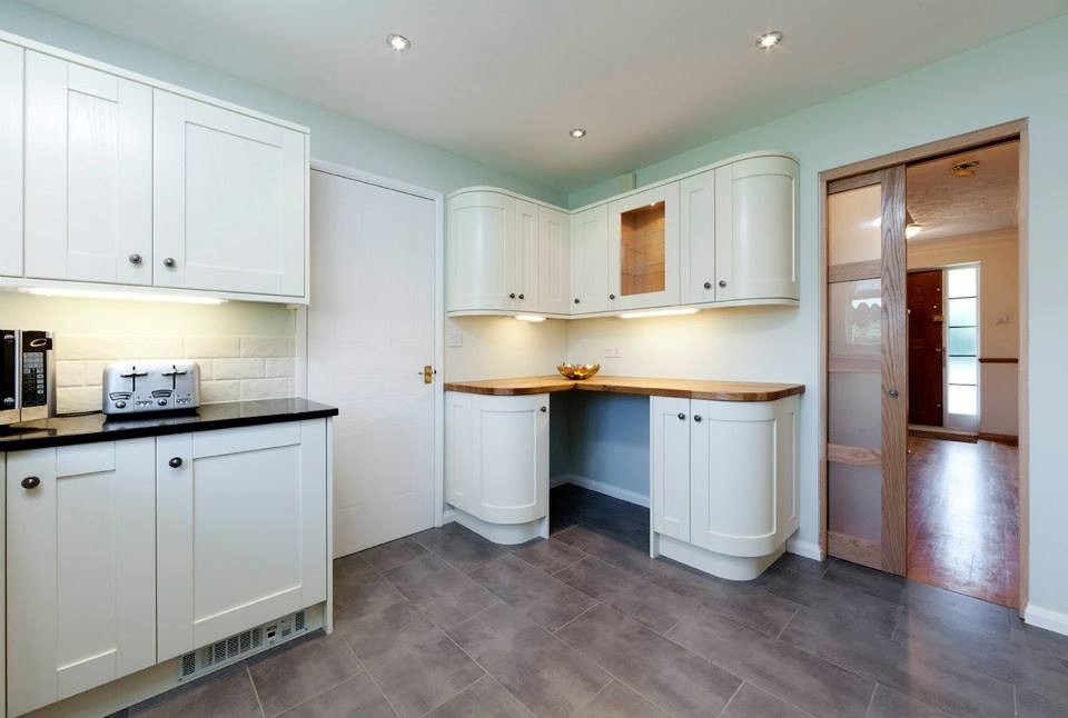 Photo of a large classic grey and cream u-shaped enclosed kitchen in London with a double-bowl sink, shaker cabinets, beige cabinets, quartz worktops, beige splashback, cement tile splashback, black appliances and porcelain flooring.