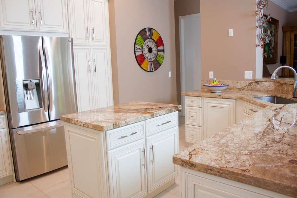 Mid-sized tuscan single-wall porcelain tile open concept kitchen photo in Miami with an undermount sink, raised-panel cabinets, white cabinets, quartzite countertops, beige backsplash, stone tile backsplash, stainless steel appliances and an island