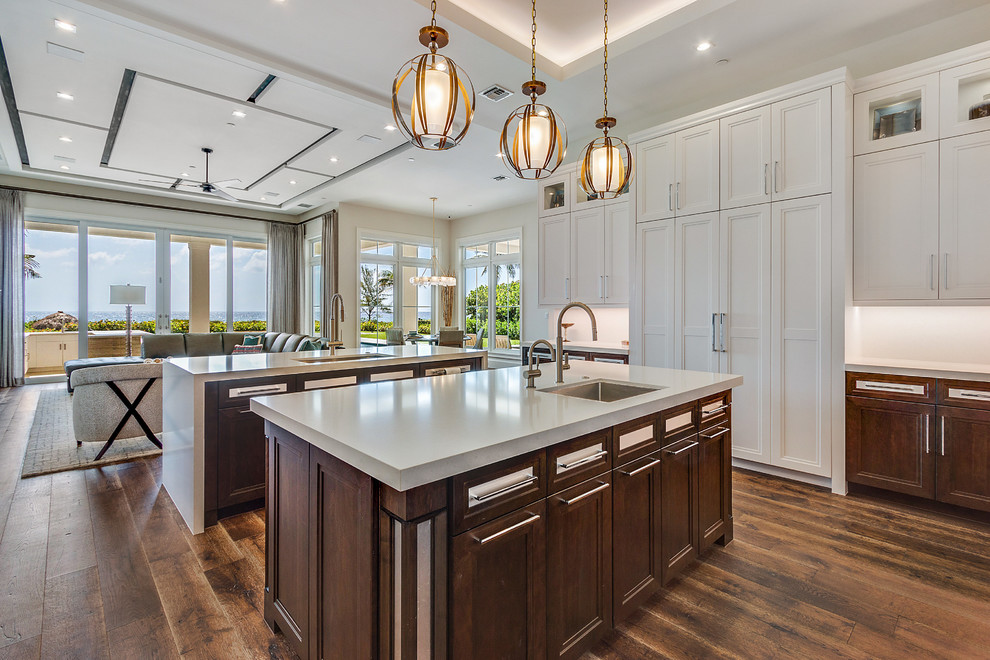 Huge beach style l-shaped dark wood floor and brown floor open concept kitchen photo in Miami with an undermount sink, recessed-panel cabinets, medium tone wood cabinets, quartzite countertops, white backsplash, stainless steel appliances and two islands