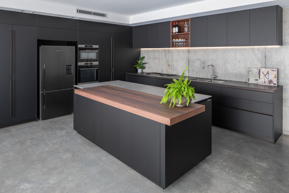 Eklektisk inredning av ett stort grå grått kök med öppen planlösning, med en undermonterad diskho, grönt stänkskydd, stänkskydd i glaskakel, integrerade vitvaror, betonggolv och en köksö