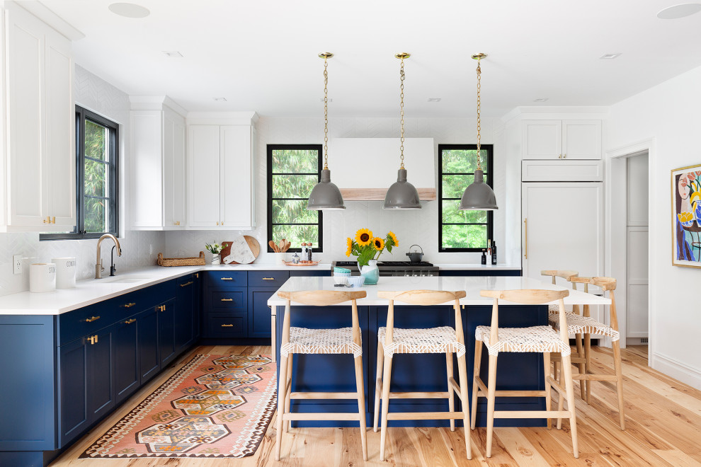 Foto di una cucina stile marino con lavello sottopiano, ante in stile shaker, ante blu, paraspruzzi bianco, elettrodomestici in acciaio inossidabile, parquet chiaro, pavimento beige e top bianco