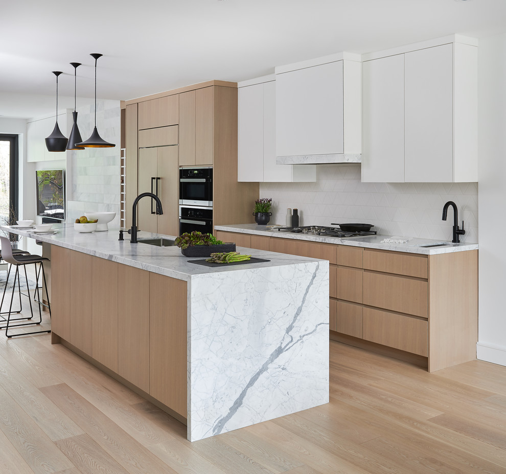 Immagine di una cucina design con lavello sottopiano, ante lisce, ante in legno chiaro, paraspruzzi bianco, elettrodomestici in acciaio inossidabile, parquet chiaro, pavimento beige e top bianco