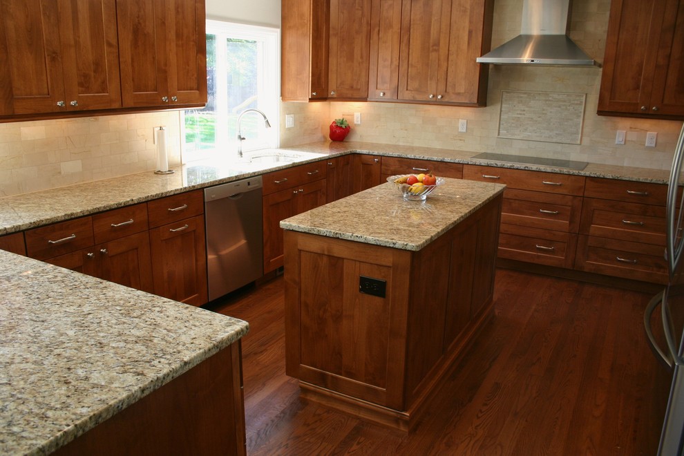 Transitional l-shaped medium tone wood floor eat-in kitchen photo in Denver with an undermount sink, recessed-panel cabinets, medium tone wood cabinets, granite countertops, beige backsplash, ceramic backsplash, stainless steel appliances and an island