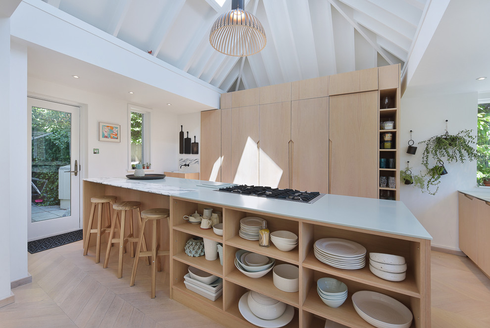 Example of a mid-sized danish light wood floor and beige floor kitchen design in London with flat-panel cabinets, light wood cabinets, marble countertops, an island and gray countertops