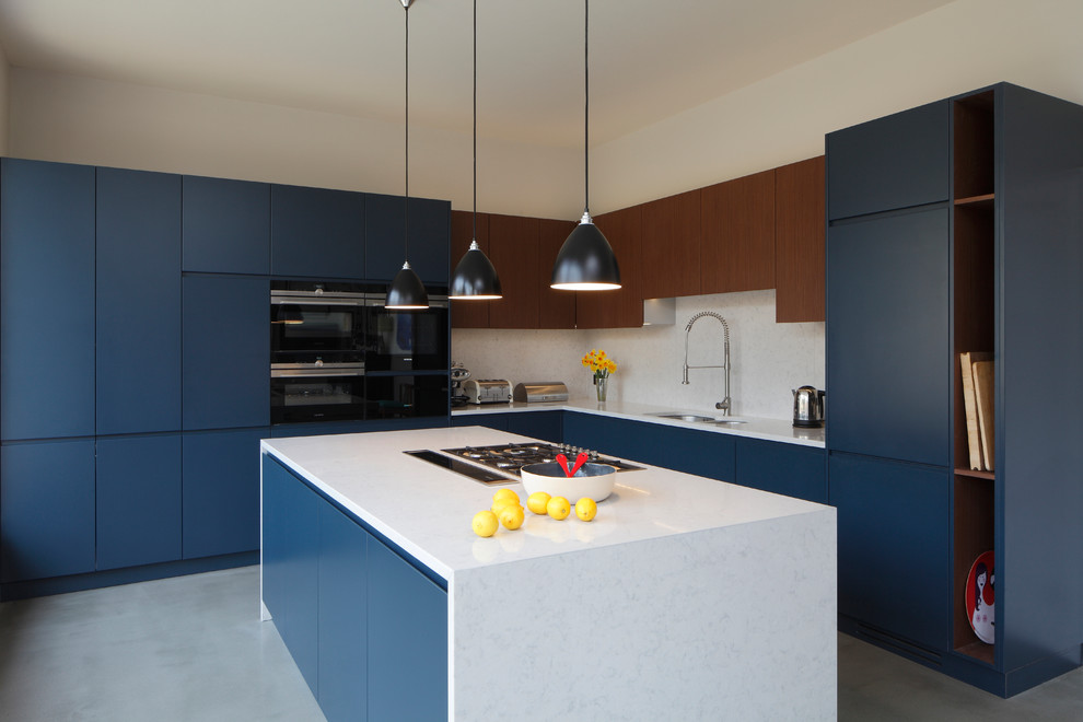 Inspiration for a large contemporary l-shaped open plan kitchen in London with flat-panel cabinets, blue cabinets, white splashback, concrete flooring, an island, grey floors, white worktops, an integrated sink, quartz worktops, stone slab splashback and integrated appliances.
