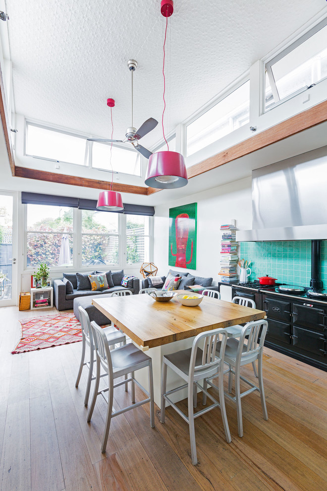Свежая идея для дизайна: кухня-гостиная в стиле фьюжн с островом, синим фартуком, светлым паркетным полом и шторами на окнах - отличное фото интерьера