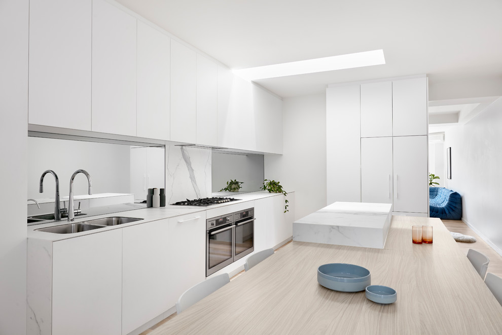 This is an example of a large modern single-wall kitchen pantry in Melbourne with beaded cabinets, white cabinets, marble worktops, white splashback, marble splashback, stainless steel appliances, slate flooring, an island, white floors and white worktops.