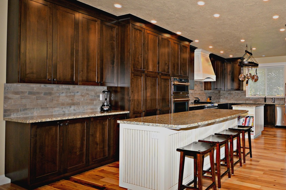 Idéer för att renovera ett stort vintage flerfärgad flerfärgat kök, med en undermonterad diskho, luckor med infälld panel, skåp i mörkt trä, granitbänkskiva, flerfärgad stänkskydd, stänkskydd i travertin, rostfria vitvaror, ljust trägolv, flera köksöar och brunt golv