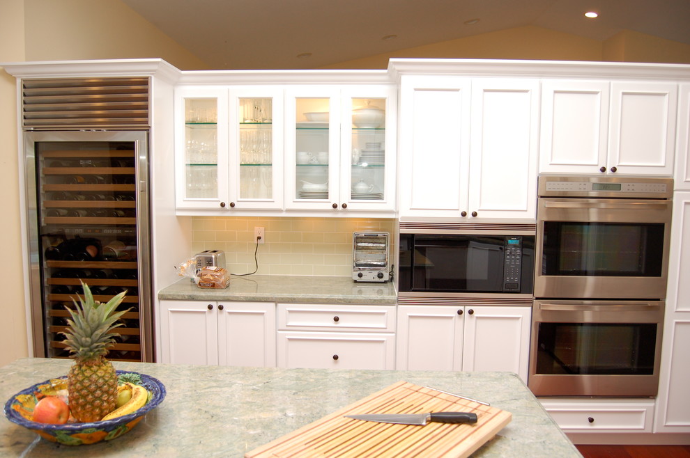 Example of a mid-sized classic medium tone wood floor eat-in kitchen design in Miami with a double-bowl sink, white cabinets, subway tile backsplash, stainless steel appliances and an island