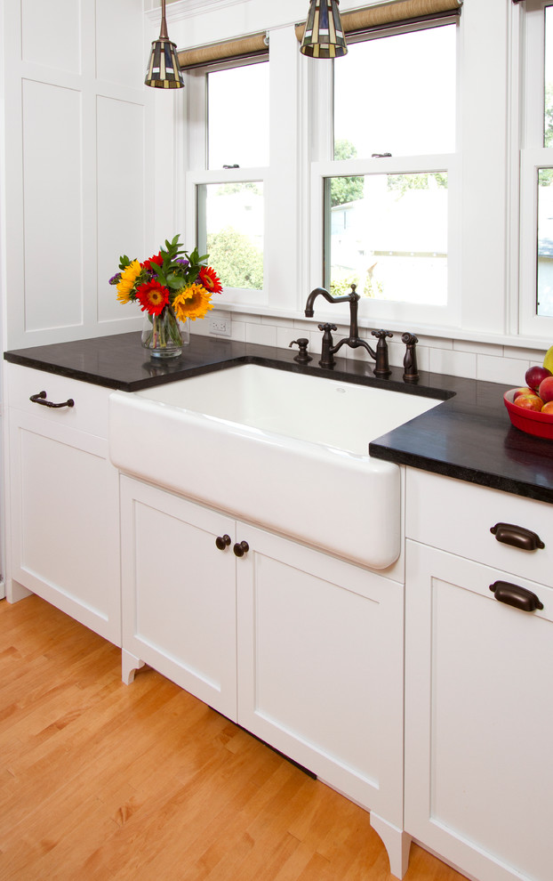 Arts and crafts l-shaped eat-in kitchen photo in Minneapolis with a farmhouse sink, shaker cabinets, white cabinets, soapstone countertops, white backsplash and subway tile backsplash