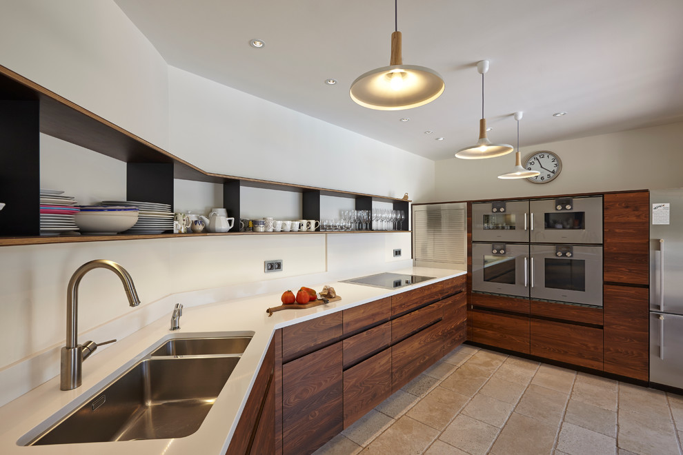 Große, Geschlossene Moderne Küche ohne Insel in L-Form mit Doppelwaschbecken, dunklen Holzschränken, Küchenrückwand in Weiß und Küchengeräten aus Edelstahl in Sonstige