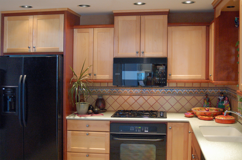 Idéer för avskilda, små amerikanska grönt l-kök, med en integrerad diskho, luckor med infälld panel, skåp i ljust trä, bänkskiva i koppar, gult stänkskydd, stänkskydd i keramik, svarta vitvaror och travertin golv