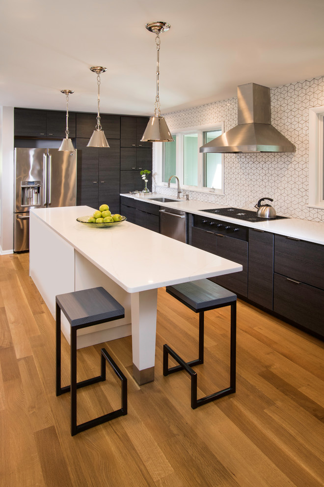 Photo of a medium sized contemporary u-shaped open plan kitchen in New York with a submerged sink, flat-panel cabinets, black cabinets, composite countertops, white splashback, ceramic splashback, stainless steel appliances, light hardwood flooring, multiple islands, brown floors and white worktops.