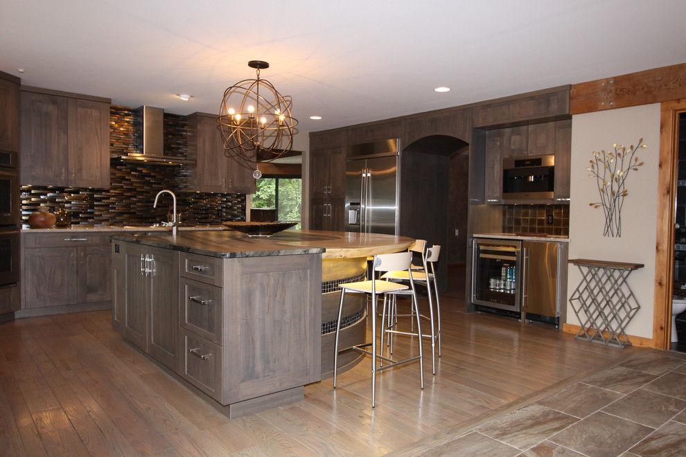 Example of a large minimalist u-shaped medium tone wood floor and brown floor eat-in kitchen design in Cleveland with an undermount sink, shaker cabinets, gray cabinets, granite countertops, metallic backsplash, glass tile backsplash, stainless steel appliances and an island