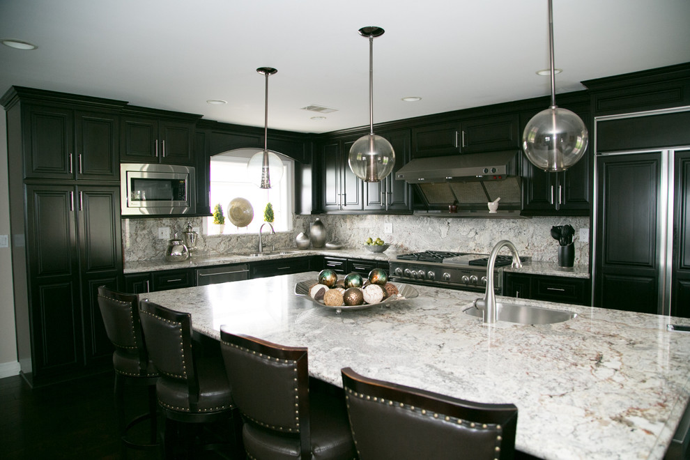 Large transitional dark wood floor eat-in kitchen photo in Los Angeles with an undermount sink, raised-panel cabinets, brown cabinets, granite countertops, multicolored backsplash, stone slab backsplash, stainless steel appliances and an island