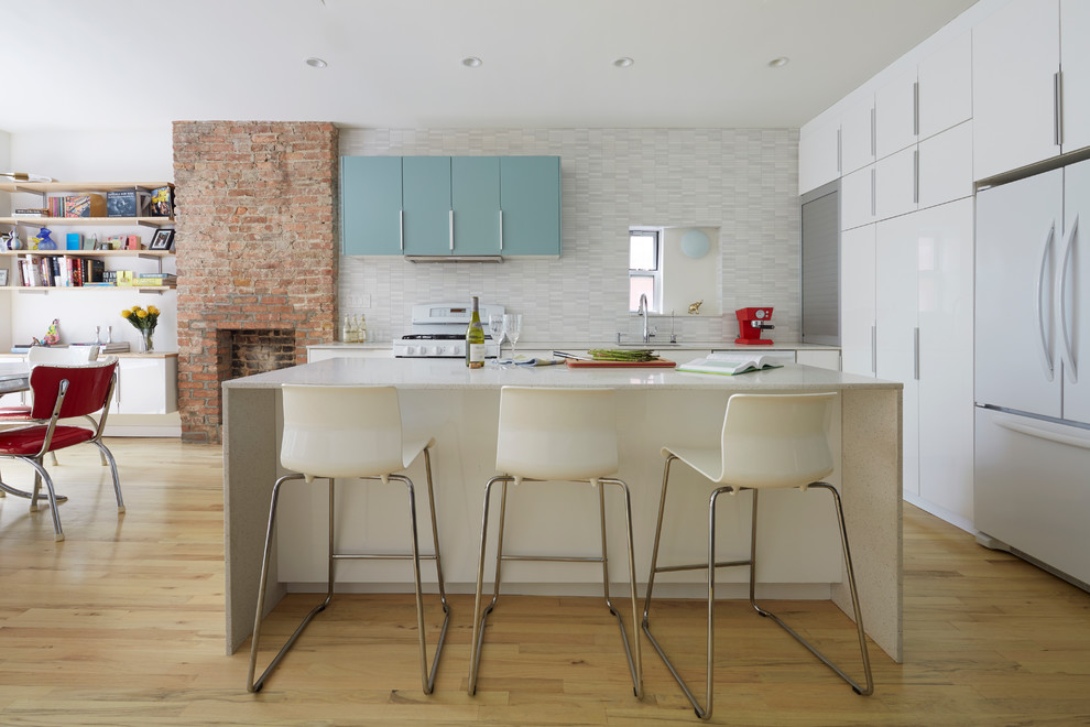 This is an example of a contemporary l-shaped open plan kitchen in New York with flat-panel cabinets, white cabinets, multi-coloured splashback and an island.