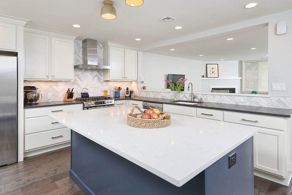 Photo of a medium sized classic l-shaped enclosed kitchen in Philadelphia with a submerged sink, flat-panel cabinets, white cabinets, engineered stone countertops, grey splashback, stone tiled splashback, stainless steel appliances, dark hardwood flooring, an island and brown floors.