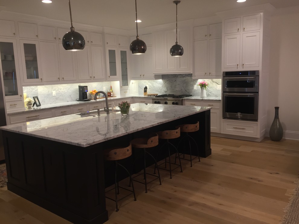 Inspiration for a large modern galley light wood floor and yellow floor eat-in kitchen remodel in Tampa with an undermount sink, raised-panel cabinets, white cabinets, quartz countertops, multicolored backsplash, marble backsplash, stainless steel appliances and an island