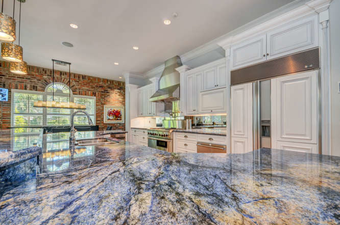 Example of a huge transitional u-shaped dark wood floor and brown floor eat-in kitchen design in Tampa with an undermount sink, raised-panel cabinets, white cabinets, granite countertops, mirror backsplash, paneled appliances and an island