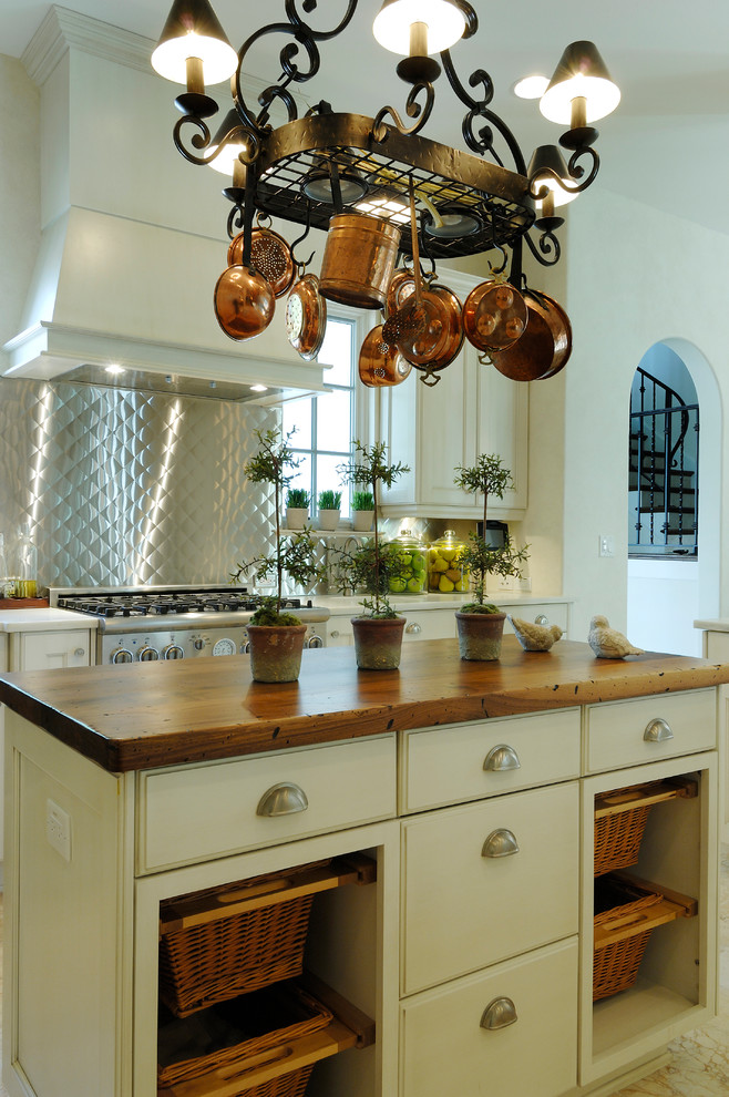 Bild på ett medelhavsstil kök, med träbänkskiva, stänkskydd med metallisk yta och en köksö