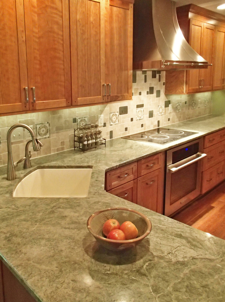 Exempel på ett stort klassiskt kök, med en undermonterad diskho, luckor med infälld panel, skåp i mellenmörkt trä, granitbänkskiva, grönt stänkskydd, glaspanel som stänkskydd, rostfria vitvaror, mellanmörkt trägolv, en halv köksö och brunt golv