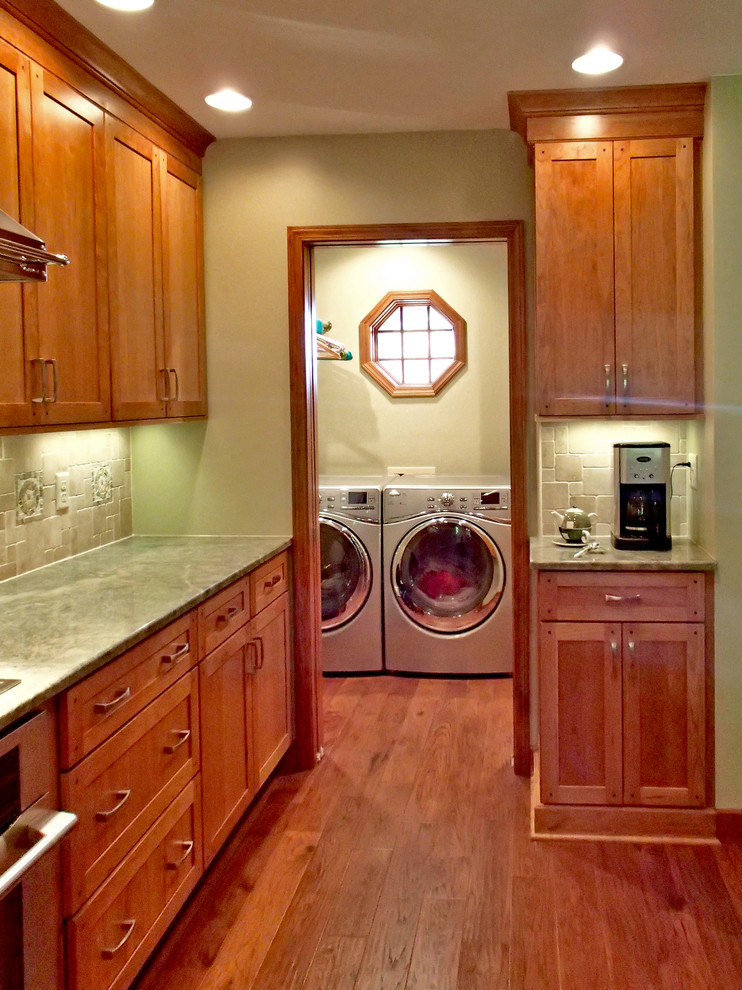 Large kitchen pantry in New York with a submerged sink, recessed-panel cabinets, medium wood cabinets, granite worktops, green splashback, glass sheet splashback, stainless steel appliances, medium hardwood flooring and a breakfast bar.