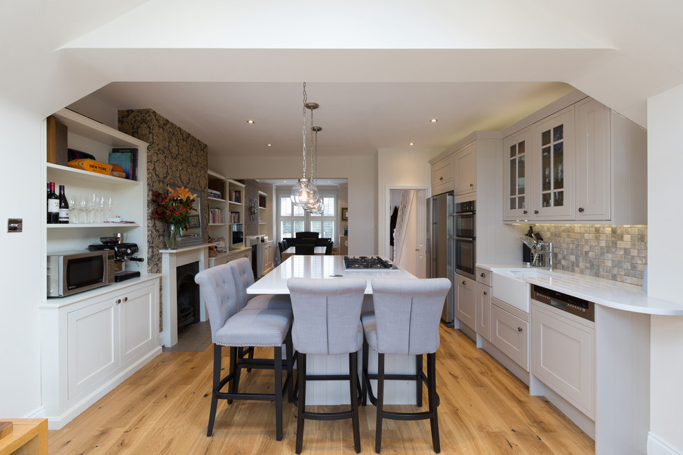 Immagine di una cucina con lavello stile country, ante in stile shaker, elettrodomestici neri e pavimento in laminato
