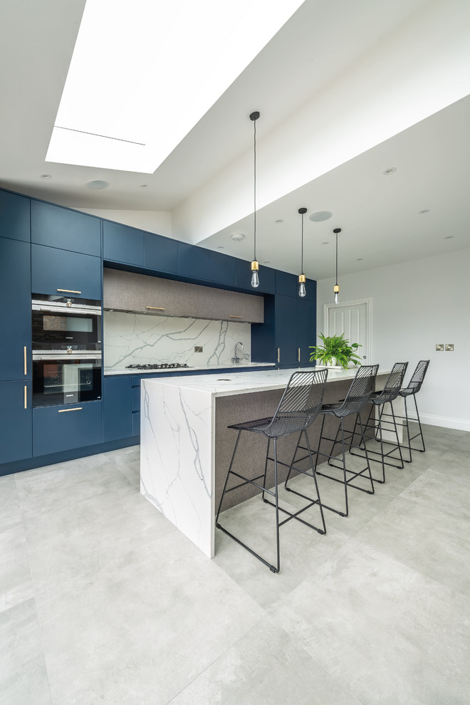 Design ideas for a medium sized contemporary open plan kitchen in London with a single-bowl sink, flat-panel cabinets, blue cabinets, quartz worktops, white splashback, marble splashback, stainless steel appliances, cement flooring, an island, grey floors and yellow worktops.