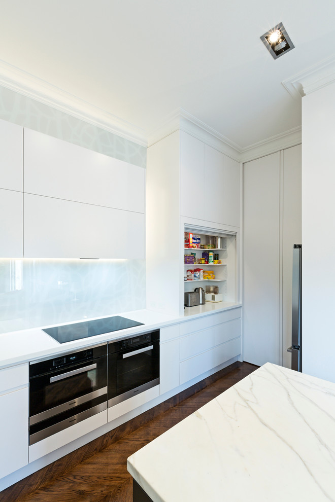 Trendy l-shaped eat-in kitchen photo in Melbourne with an integrated sink, flat-panel cabinets, white cabinets, marble countertops, gray backsplash, glass sheet backsplash and an island
