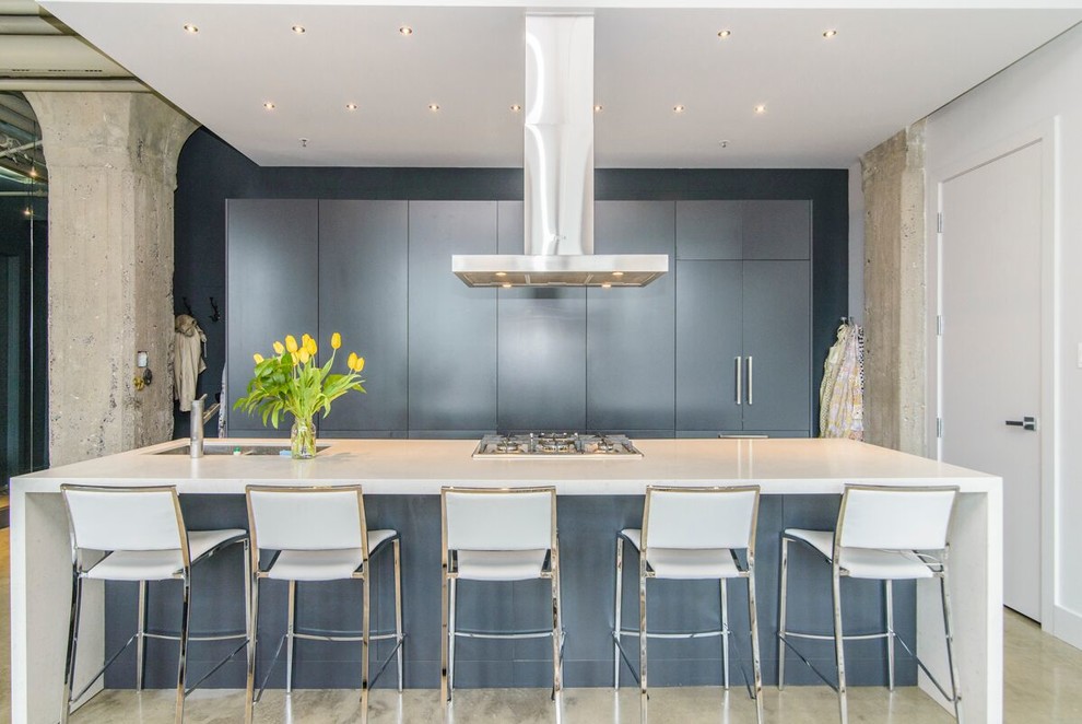 Immagine di un grande cucina con isola centrale minimal con ante lisce, top in quarzite, pavimento in cemento, lavello a doppia vasca, ante blu e pavimento grigio
