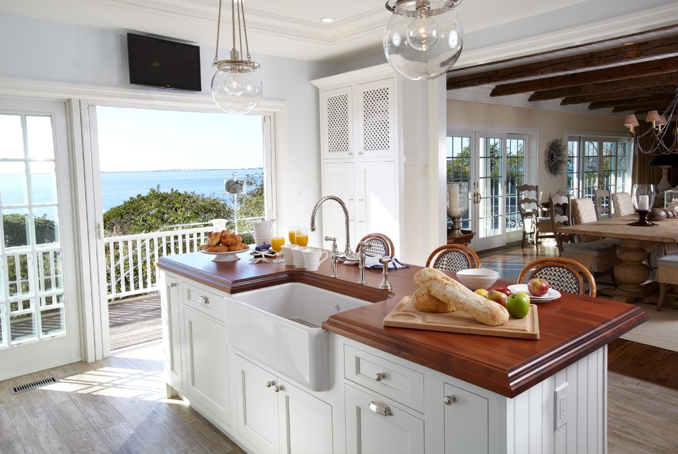 Inspiration for a large coastal l-shaped ceramic tile open concept kitchen remodel in New York with a farmhouse sink, recessed-panel cabinets, white cabinets, wood countertops, white backsplash, cement tile backsplash, stainless steel appliances and an island