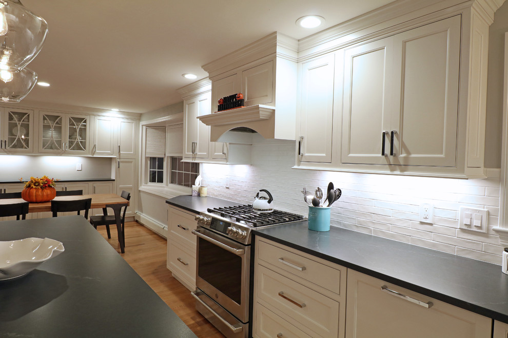 ボストンにある高級な中くらいなトランジショナルスタイルのおしゃれなキッチン (アンダーカウンターシンク、インセット扉のキャビネット、白いキャビネット、ソープストーンカウンター、白いキッチンパネル、磁器タイルのキッチンパネル、シルバーの調理設備、無垢フローリング、ベージュの床、マルチカラーのキッチンカウンター) の写真