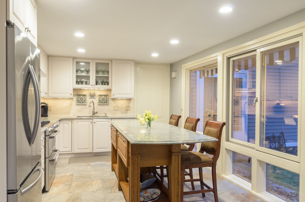 Example of a classic l-shaped eat-in kitchen design in Boston with an undermount sink, raised-panel cabinets, beige cabinets, granite countertops, ceramic backsplash, stainless steel appliances and an island