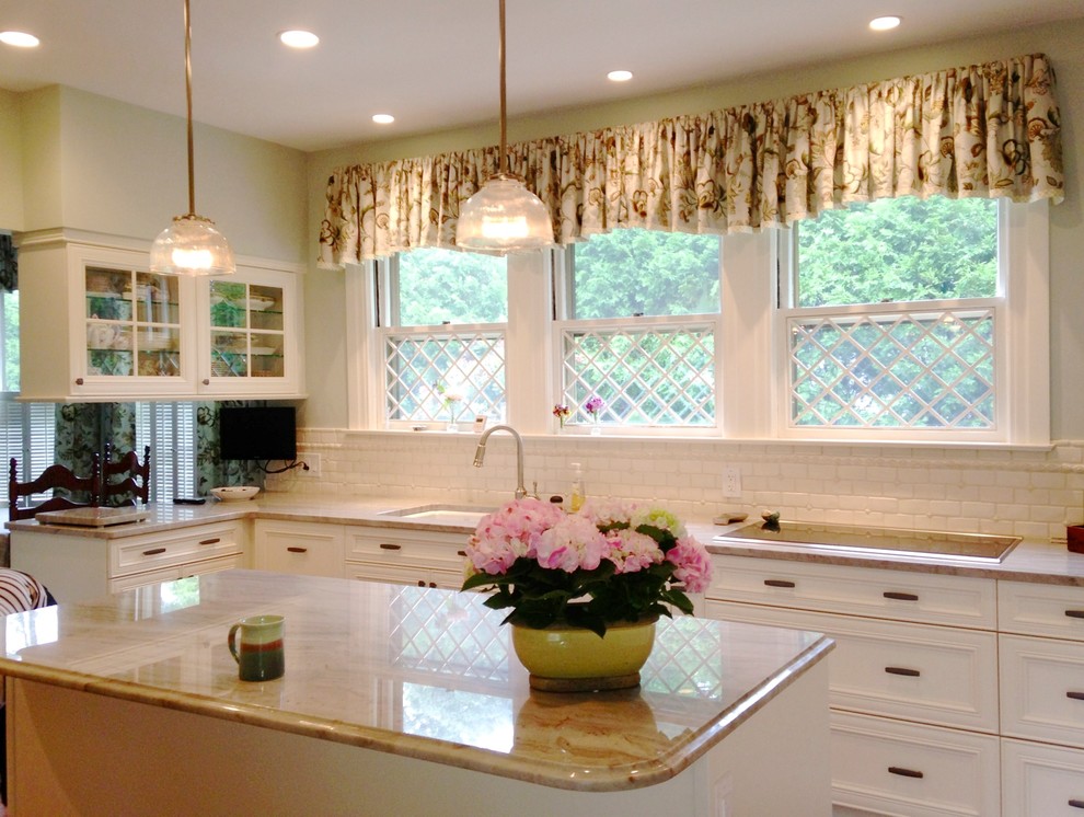 Eat-in kitchen - mid-sized traditional l-shaped medium tone wood floor and brown floor eat-in kitchen idea in Boston with an undermount sink, recessed-panel cabinets, beige cabinets, quartzite countertops, beige backsplash, subway tile backsplash, paneled appliances and an island