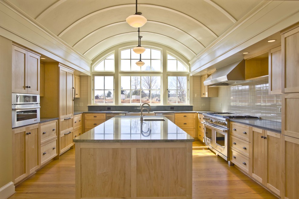 Inspiration pour une cuisine traditionnelle en U et bois clair avec un placard à porte shaker, une crédence blanche, un électroménager en acier inoxydable et parquet clair.