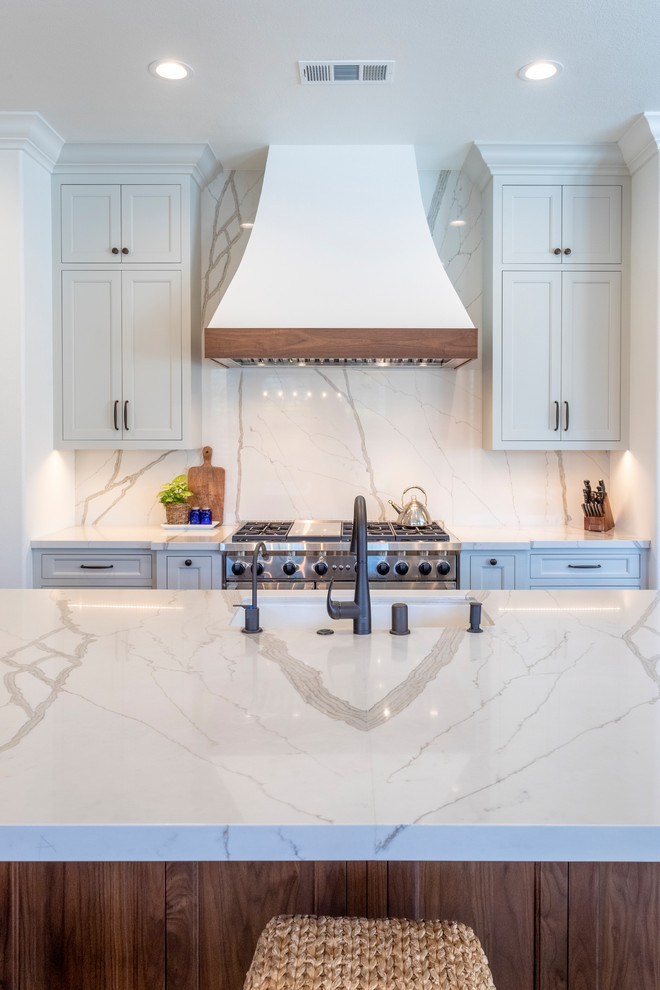 Eat-in kitchen - large transitional single-wall brown floor eat-in kitchen idea in Los Angeles with an undermount sink, shaker cabinets, white cabinets, quartzite countertops, white backsplash, stone slab backsplash, stainless steel appliances, an island and white countertops